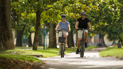 Un couple roule dans un parc avec leurs vélos pliants.