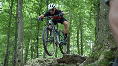 Un cycliste roule dans la forêt et vient de sauter d'une pierre.