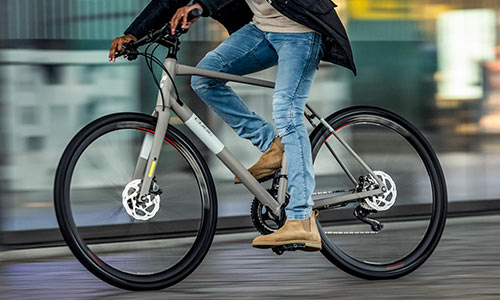 Un cycliste traverse la ville sur son vélo de fitness, il n'est que partiellement visible.